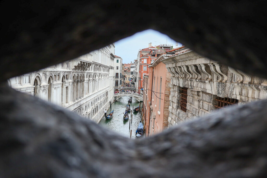 View of Venice, Italy, framed through a manmade hole in a stone fence.