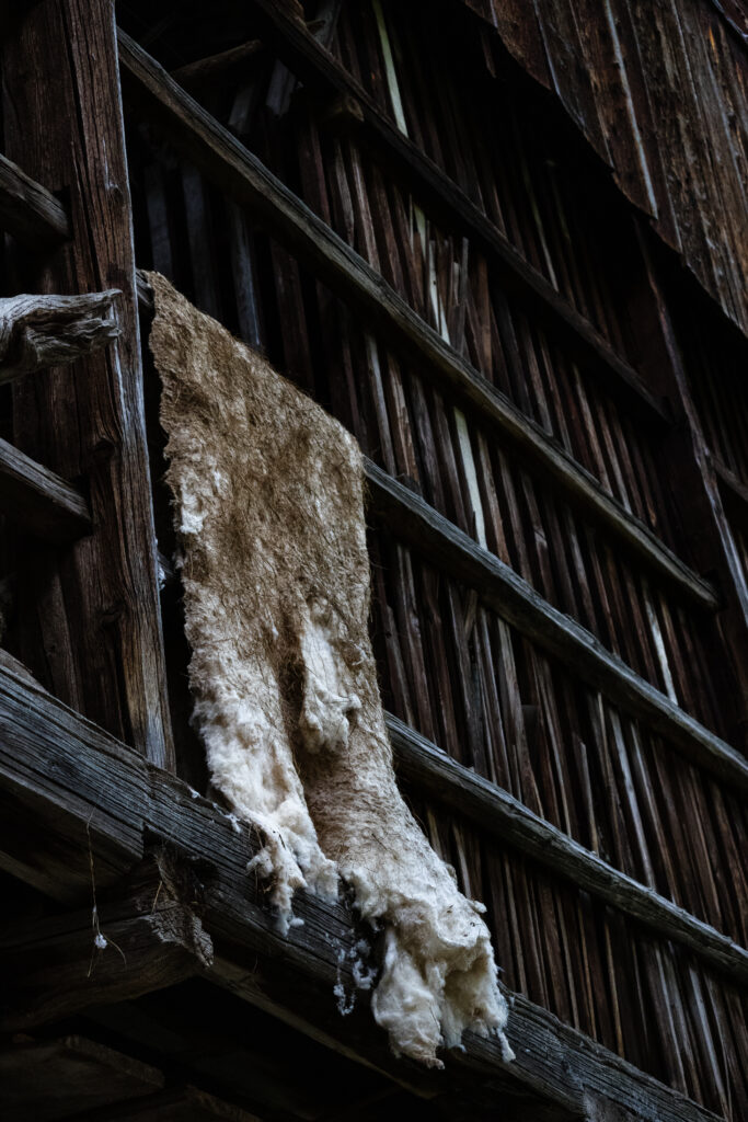 Animal fur hanging on the balcony of an old, dark wooden building.